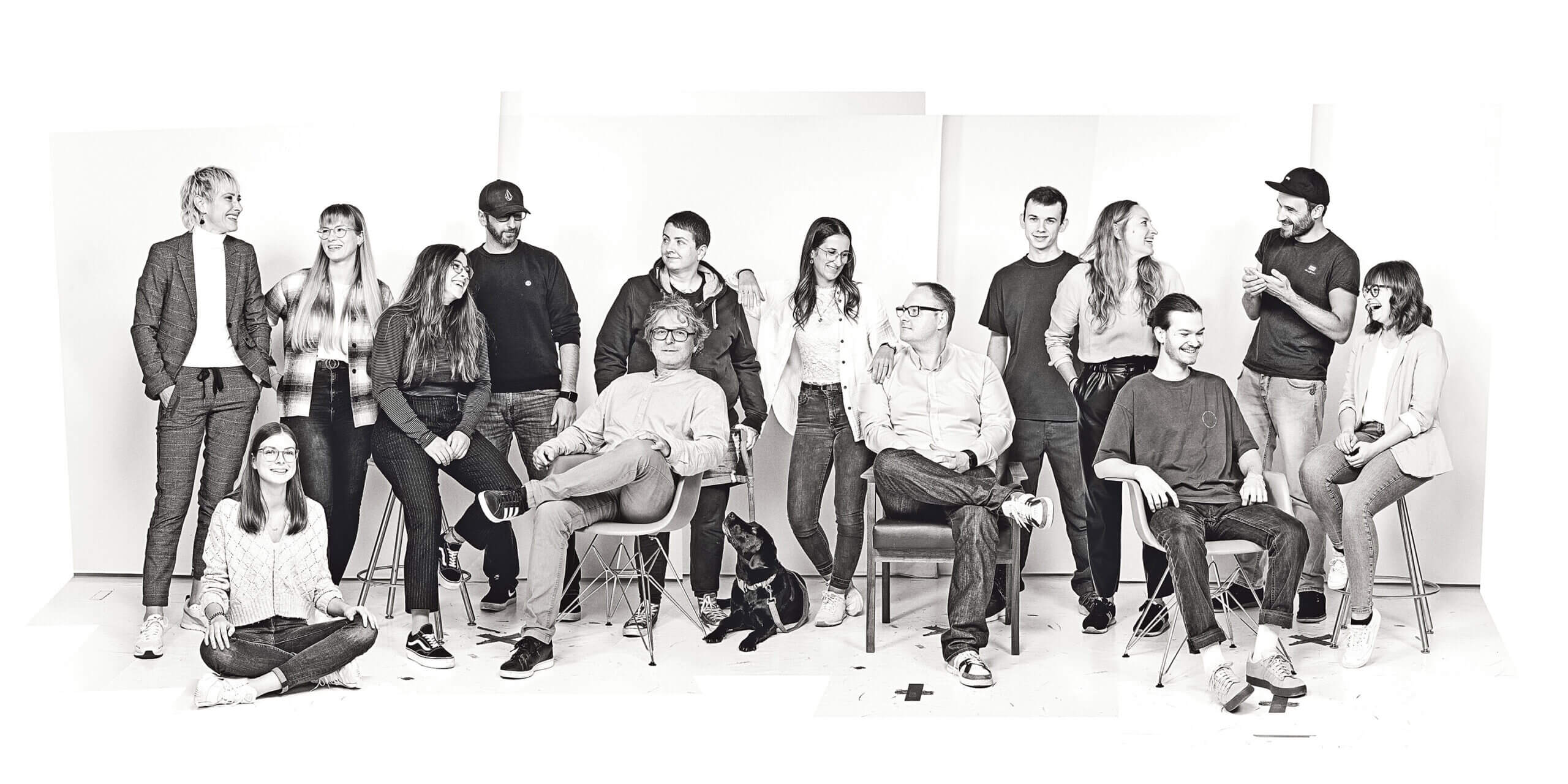 Gruppenfoto des Partner in Crime Teams mit mehreren Personen und einem Hund, alle stehen oder sitzen locker zusammen.