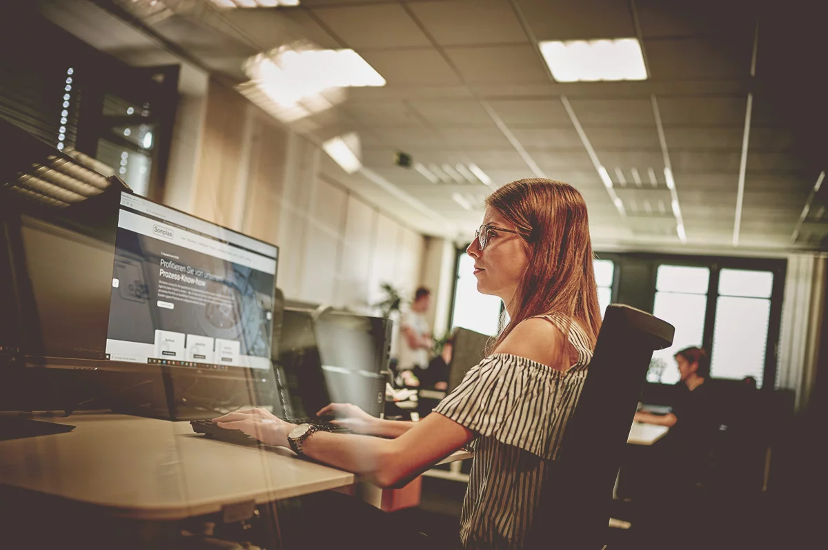 Frau arbeitet konzentriert an einem Computerbildschirm im Büro