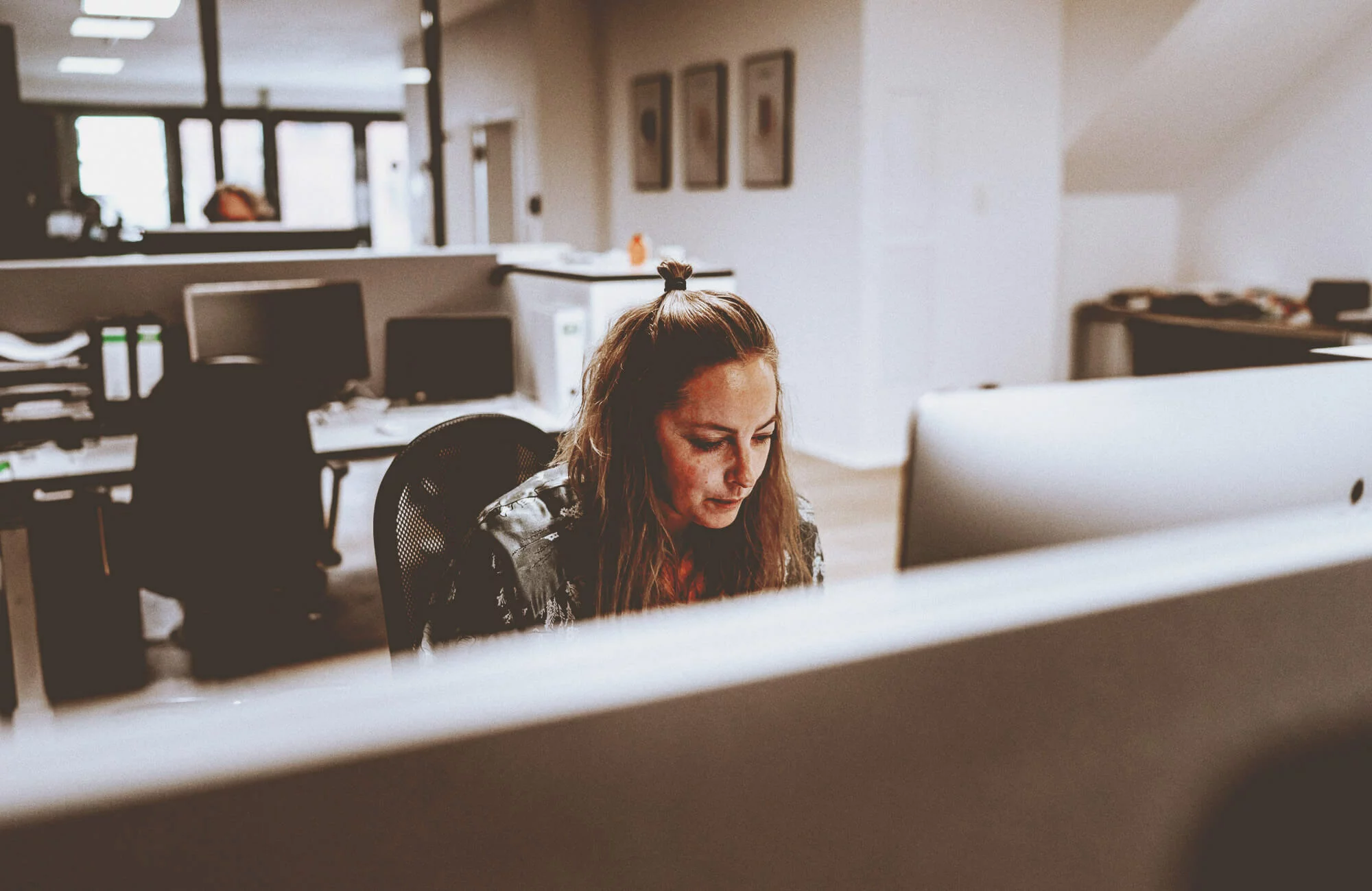 Frau sitzt im Büro am Computer und arbeitet.