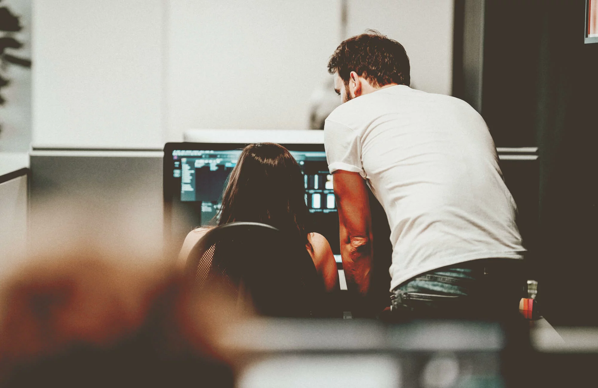 Mann und Frau arbeiten gemeinsam an einem Computerbildschirm.