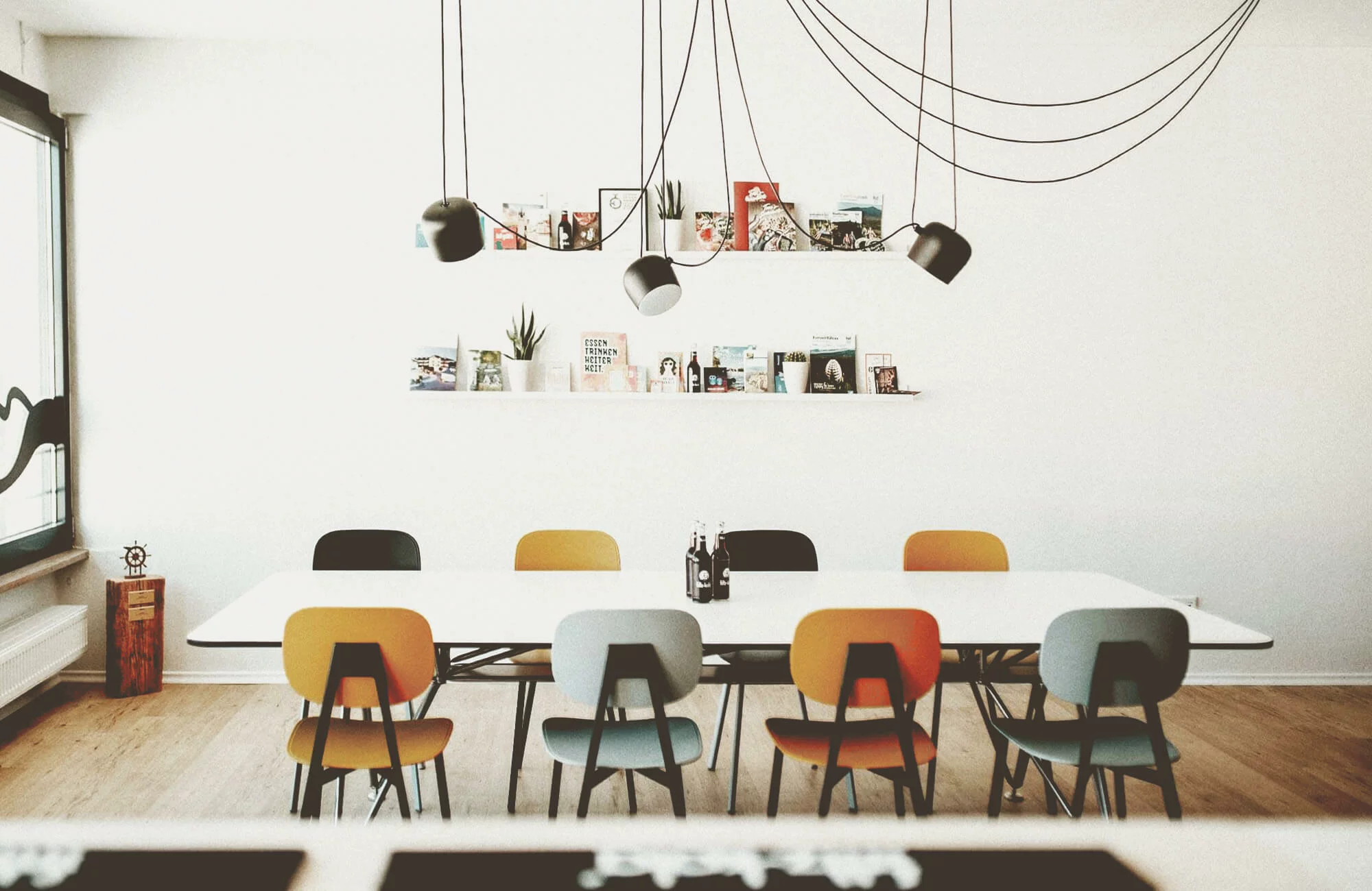 Moderner Besprechungsraum mit großem Tisch und bunten Stühlen.